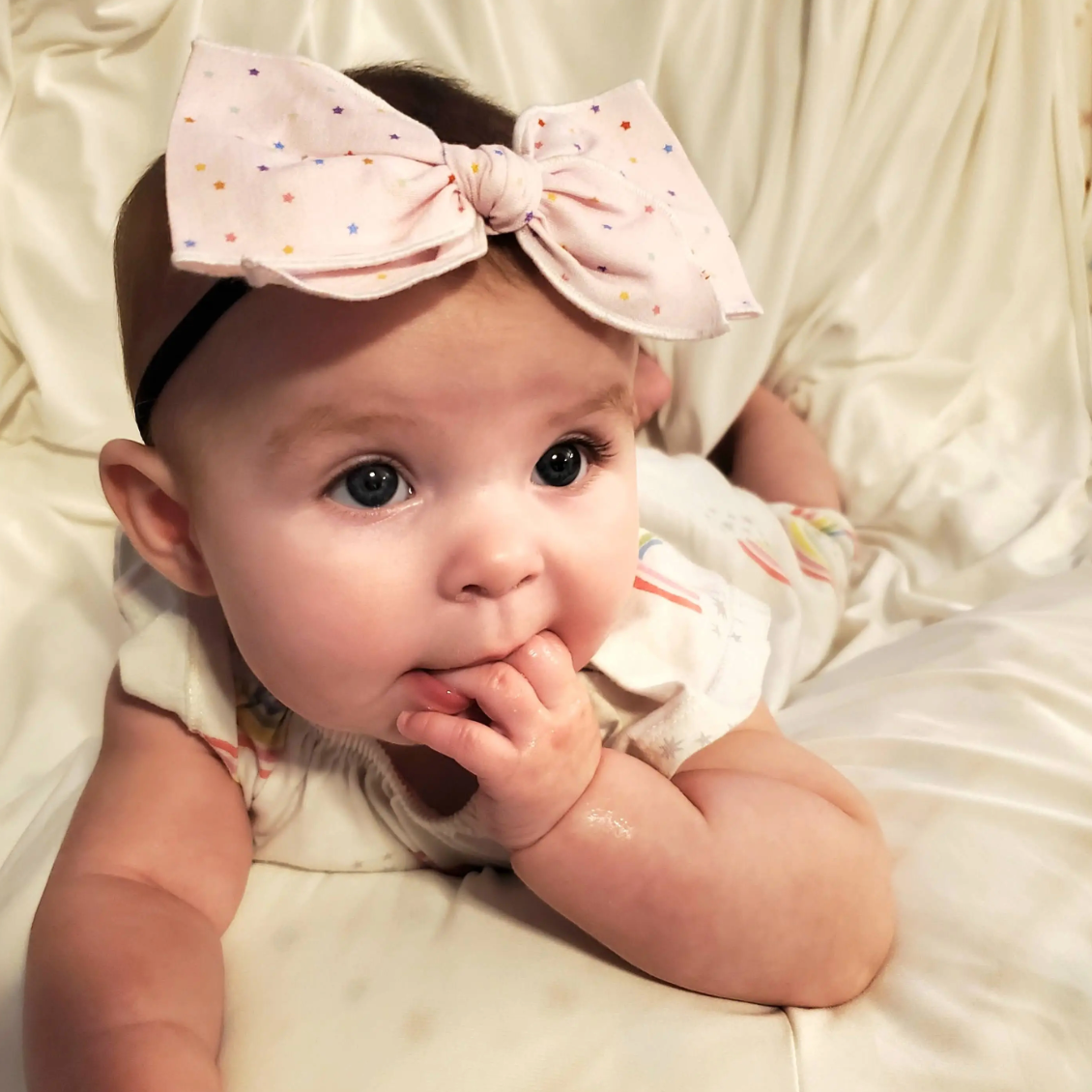 A pink with rainbow star small hemmed-edge bow made from vintage fabric.